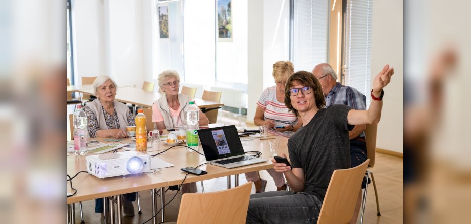 Junger Mann zeigt Senioren das Internet 