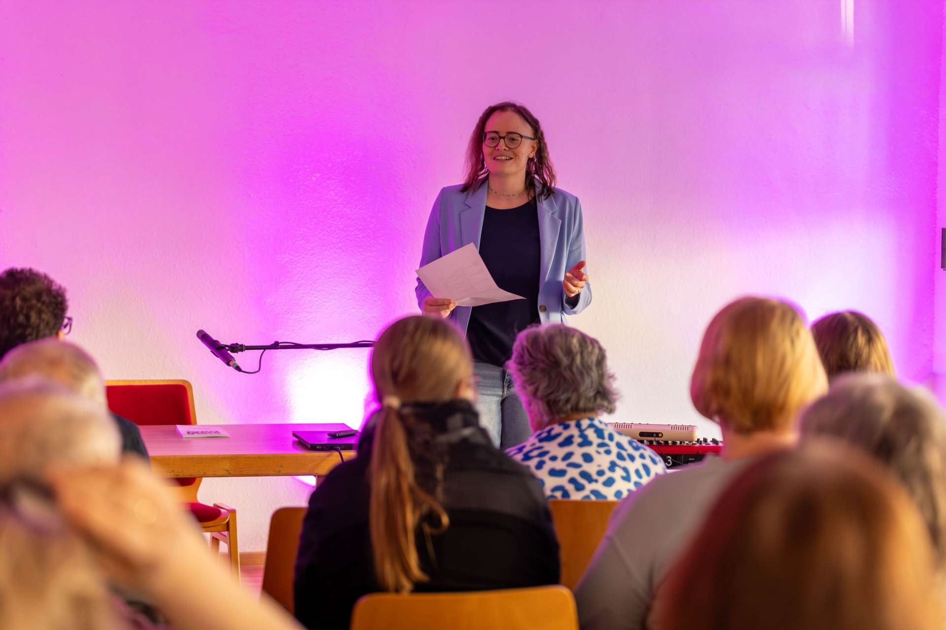 Frau steht auf Bühne vor Publikum