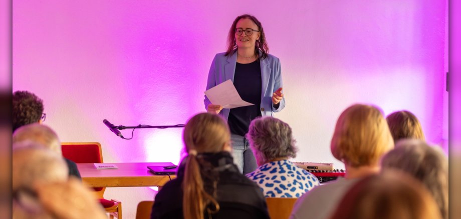 Lesung der Kurzgeschichten-Werkstatt Frau steht auf Bühne vor Publikum