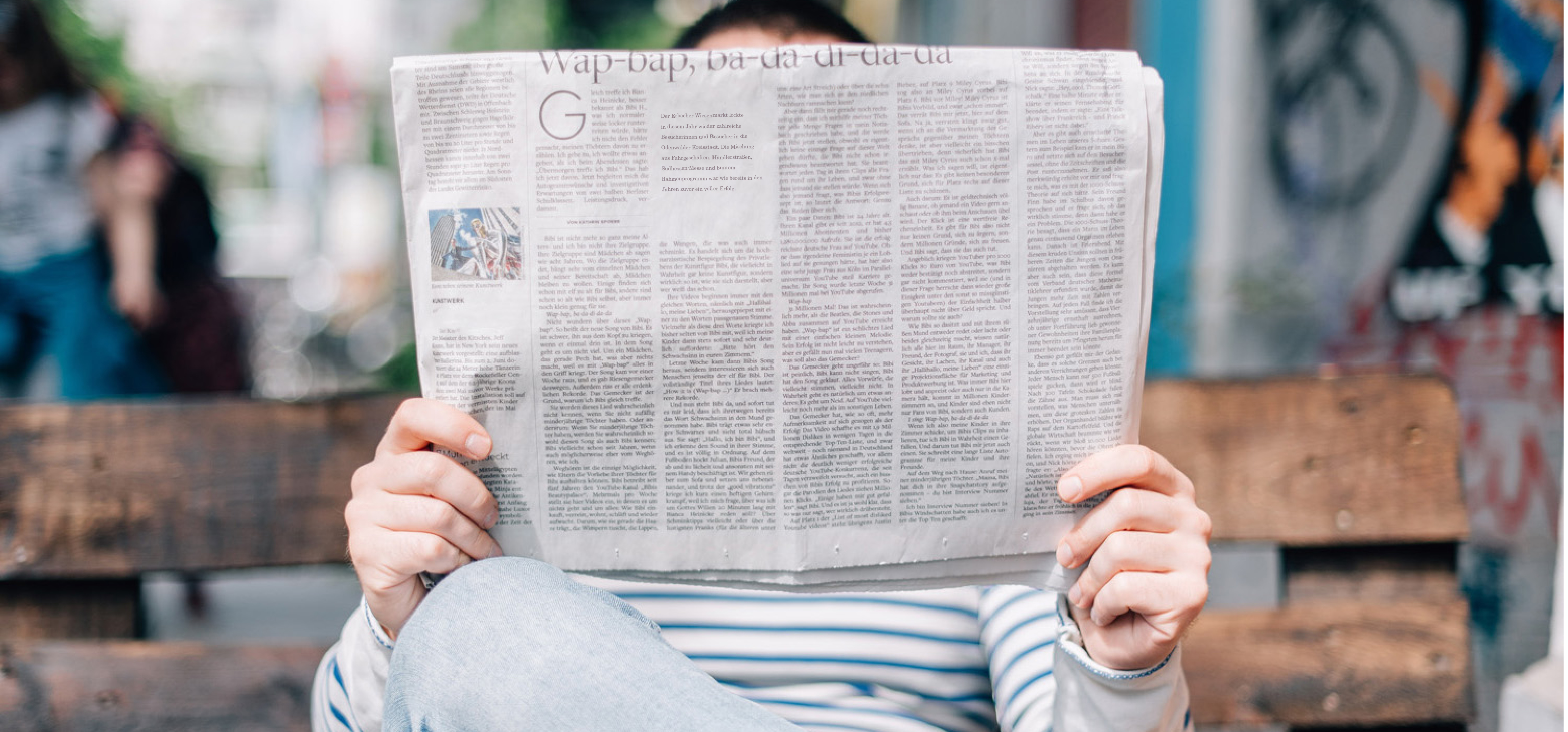 Mann auf Parkbank mit Zeitung in der Hand