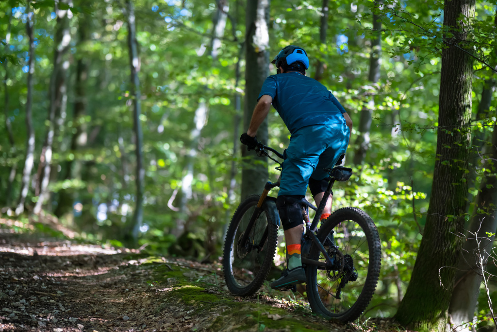 Mountainbikefahrer fährt ein Bike durch einen Wald an einem sonnigen Tag. 