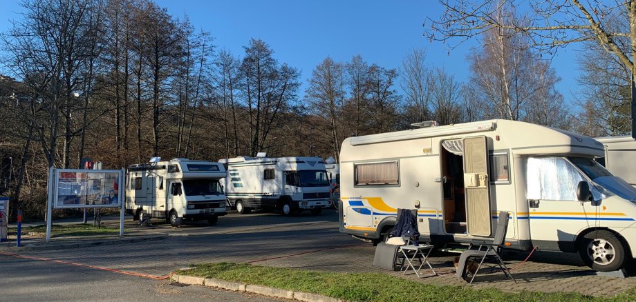 Drei Wohnmobile auf Stellplatz mit Infotafel